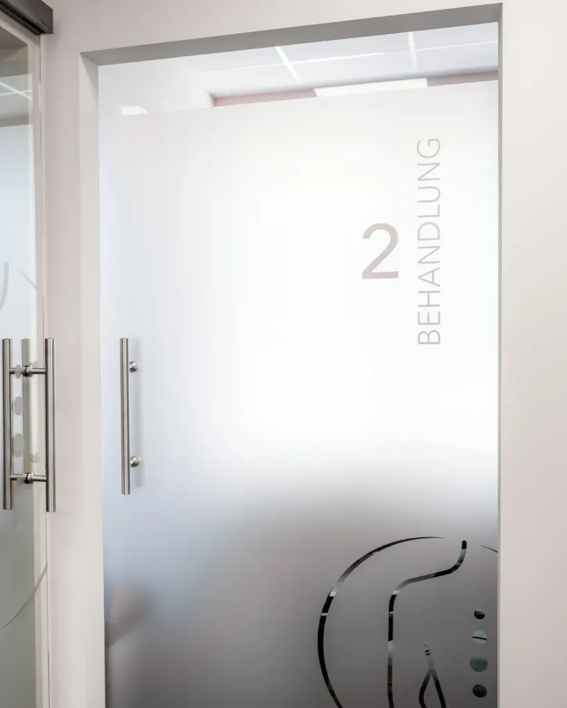 Milchglastür mit Beschriftung Behandlung 2 in der Physiotherapiepraxis Sophie Klaus