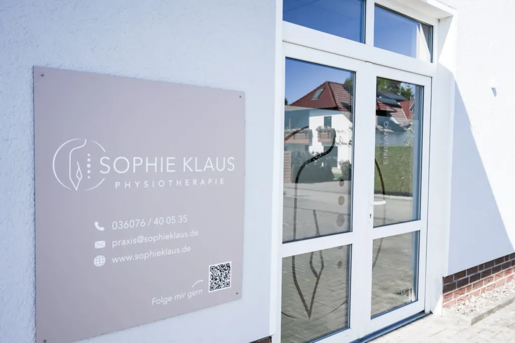 Praxisschild Sophie Klaus Physiotherapie neben dem Eingang der Praxis mit Kontaktdaten und QR-Code